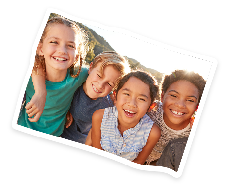 Four happy children outdoors smiling together with natural sunlight and a mountain background